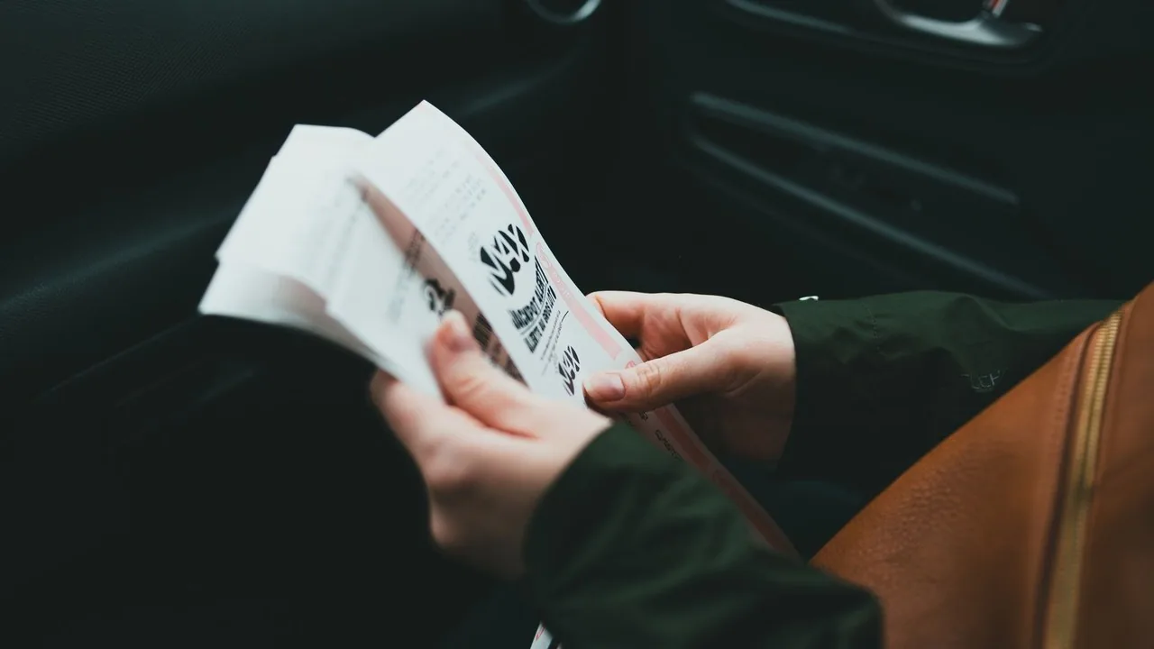 Osoba trzymająca broszurę informacyjną programu Czyste Powietrze przy biurku z laptopem