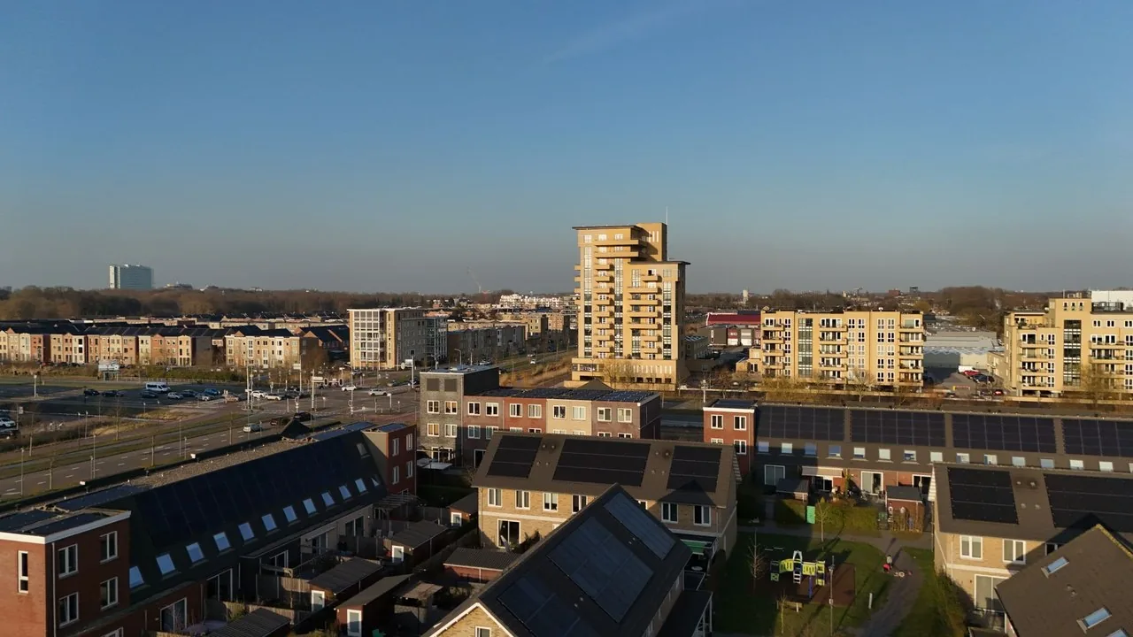 Widok z drona na osiedle mieszkaniowe, gdzie na dachach bloków zainstalowano panele fotowoltaiczne.